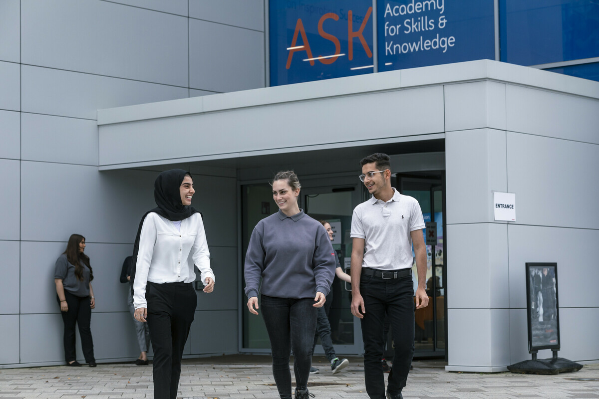 Three apprentices outside a skills academy building.