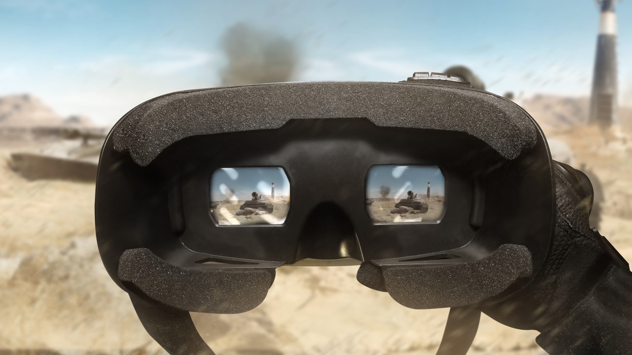 First person view soldier hand in black battle gloves & tactical jacket using vr glasses on desert tank war scene with health & armor indicator.
