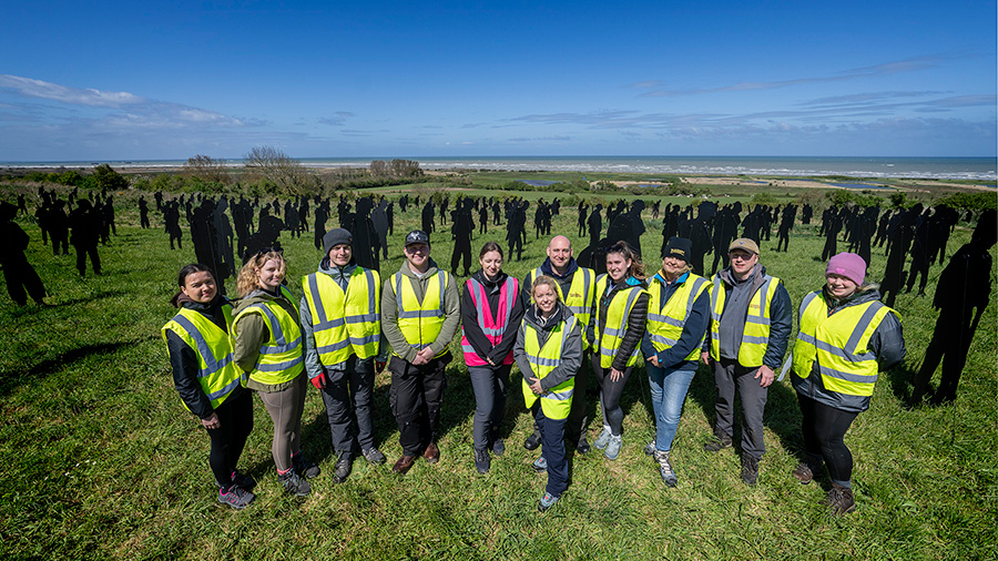 A team of volunteers poses for a photo at the Standing with Giants installation between Gold Beach and the British Normandy Memorial in Ver-sur-Mer, France.