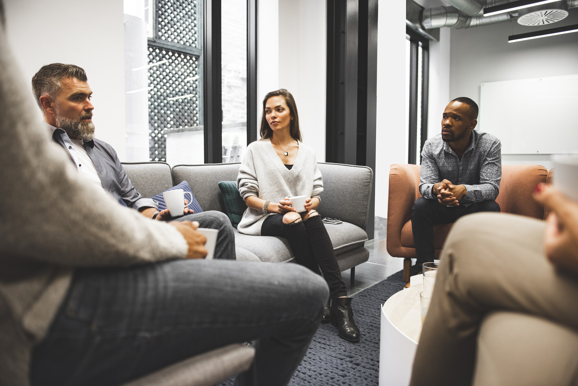 Group of business people in office cafeteria drinking coffee whilst talking to each other