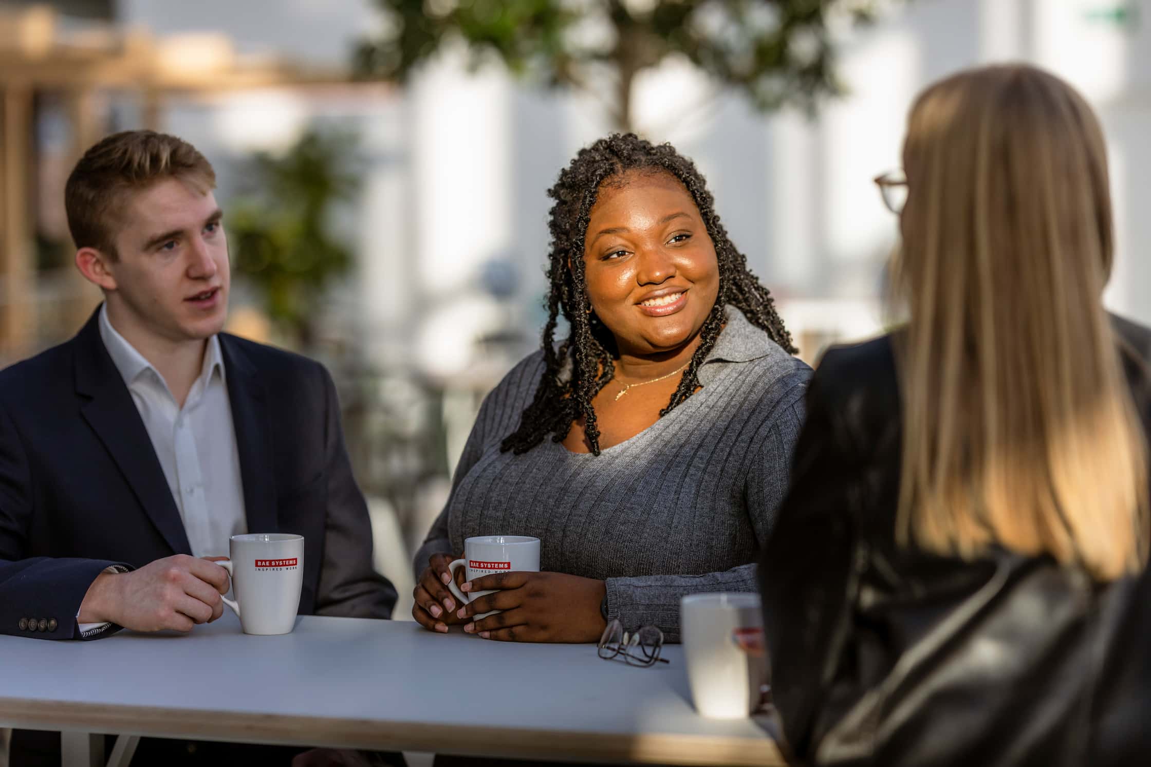 Young employees having coffee outside in the shade