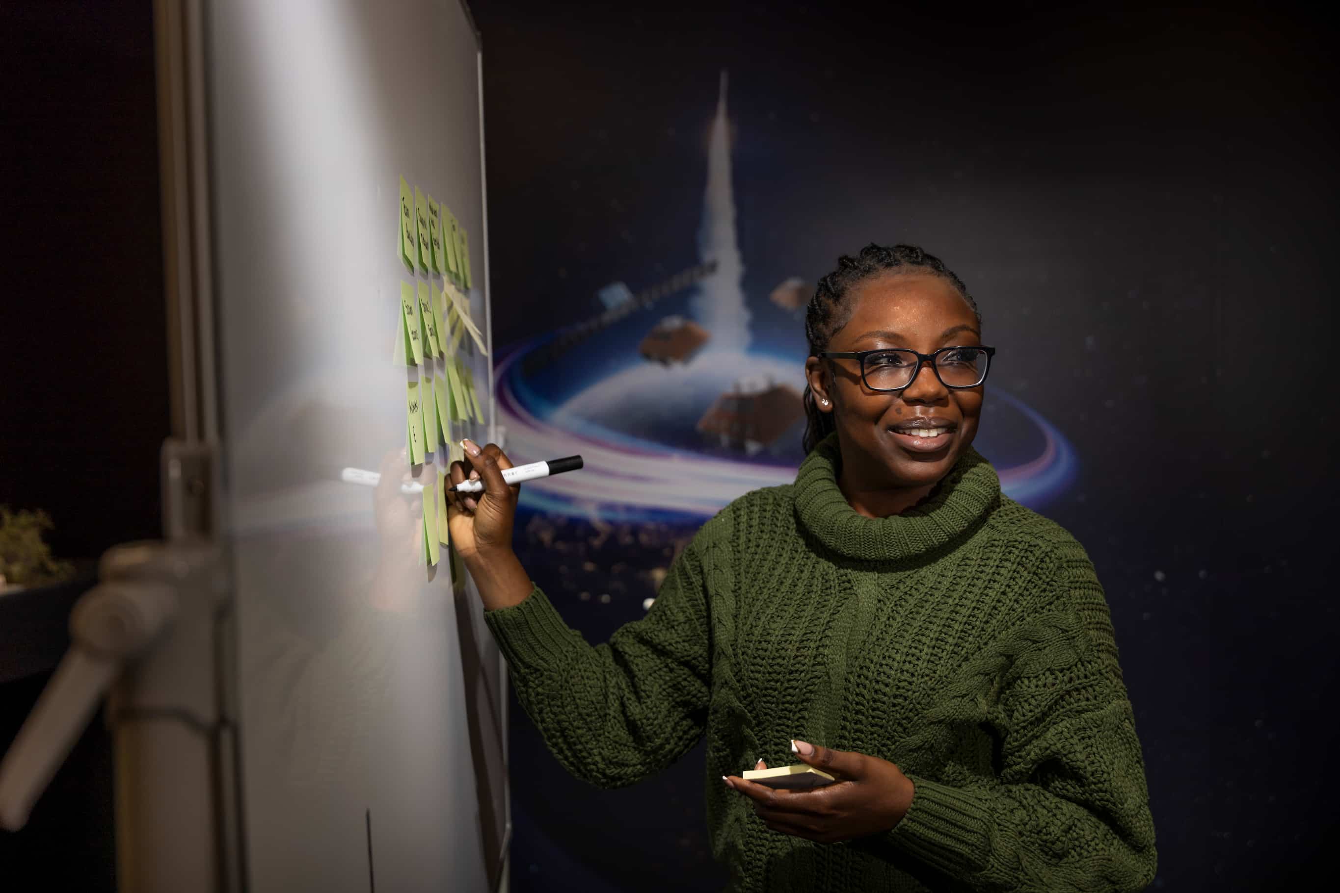 Employee writing on a whiteboard with post-it notes