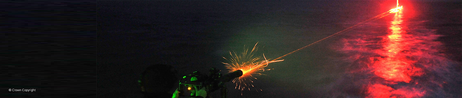 Image of naval minigun firing at night © Crown Copyright