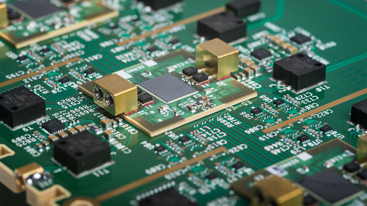 BAE Systems electrical engineers reviewing new defense electronics designs in front of new processing equipment in development BAE Systems electrical engineers reviewing new defense electronics designs in front of new processing equipment in development