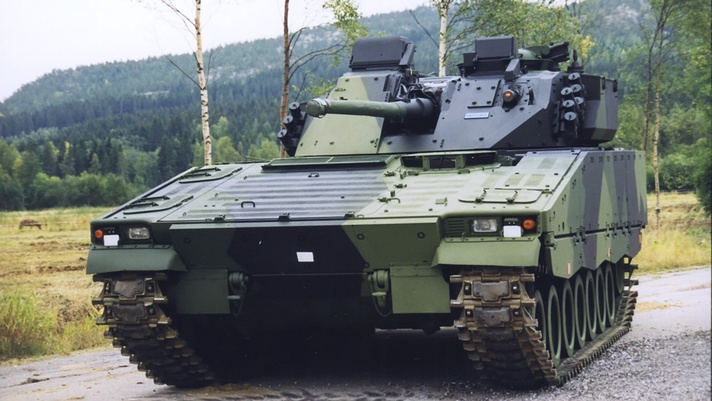 A combat-proven CV9030FIN on a gravel road in front of a green forest. Finland is the latest in a series of CV90 customers to re-invest in the infantry fighting vehicle platform.    