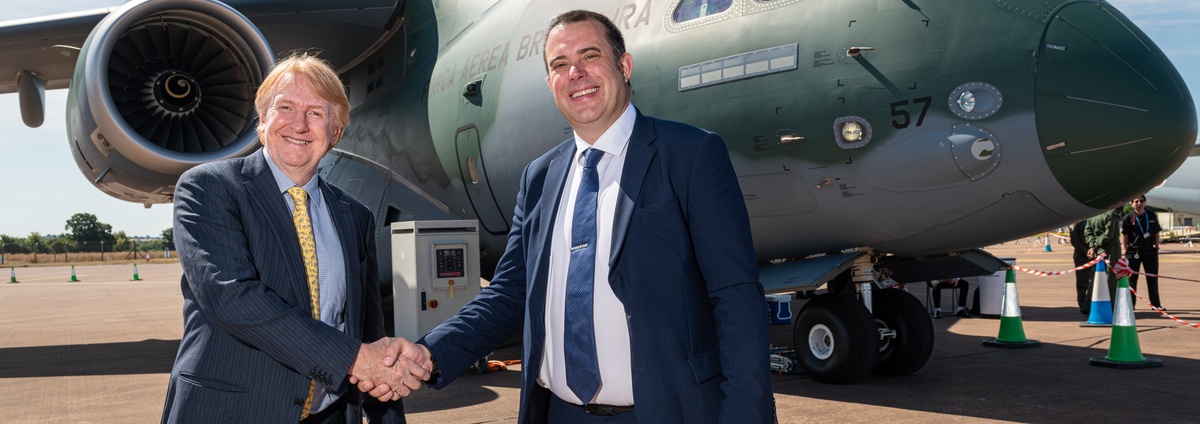 Embraer and BAE Systems shake hands in front of Embraer C390 aircraft
