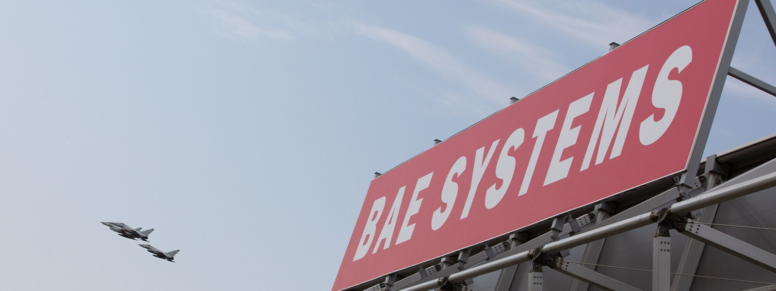 BAE Systems logo on Hall 5 at Farnborough Airshow 2022 with Eurofighter Typhoons flying in the background
