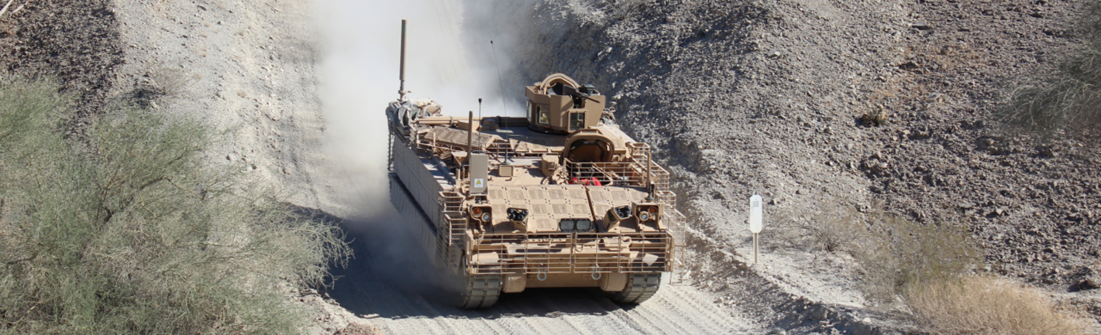 Image of the Armored Multi-Purpose Vehicle (AMPV) quickly traveling down a dirt road.
