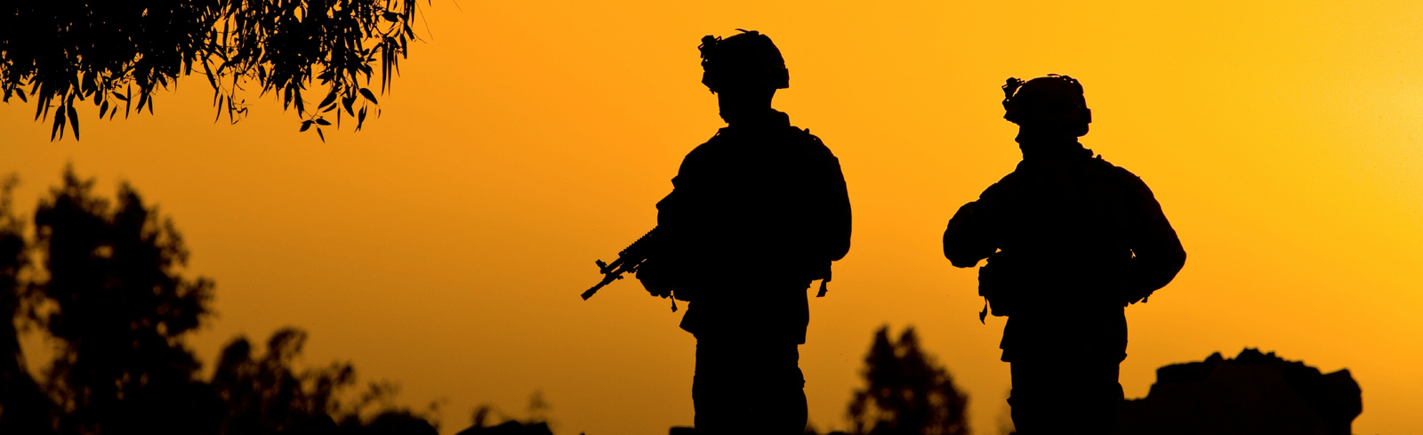 Silhouette of soldiers against orange sky