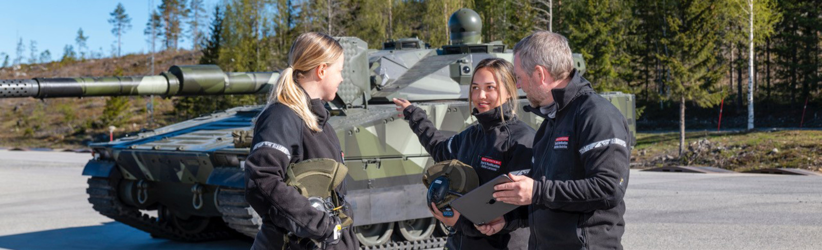 Three employees standing in front of a CV90